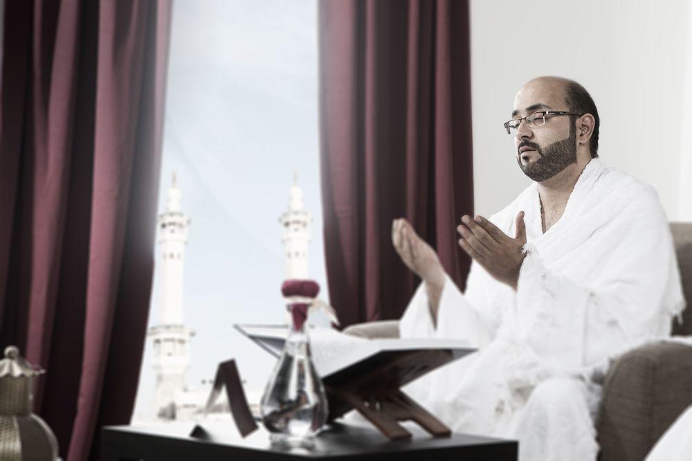 Makarem Ajyad Makkah Hotel Мека Екстериор снимка The photo depicts a man sitting in a room, wearing traditional white garments typically associated with the Hajj pilgrimage. He appears to be engaged in a prayer or spiritual practice, with his hands raised in a gesture of supplication. In the backgr