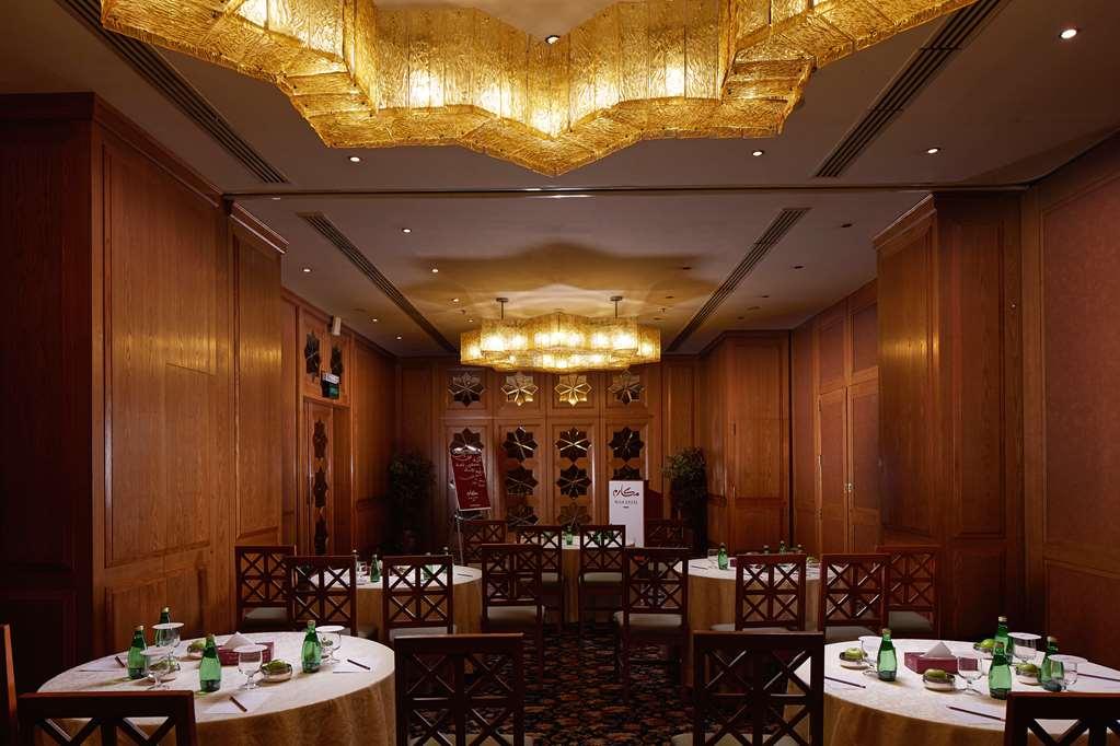 Makarem Ajyad Makkah Hotel Мека Съоръжения снимка The photo shows a well-decorated dining room with wooden paneling and elegant furnishings. There are round tables covered with tablecloths, and each table is arranged with glasses of water. The lighting is warm, provided by elaborate chandeliers on t