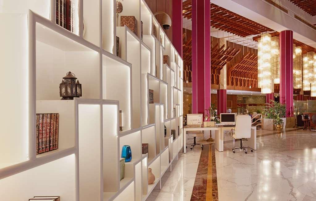 Makarem Ajyad Makkah Hotel Мека Интериор снимка The photo shows a modern interior space, likely a lobby or lounge area of a stylish hotel or building. There is a partition wall made up of white shelving units illuminated from within, displaying various decorative items, books, and vases. The desig