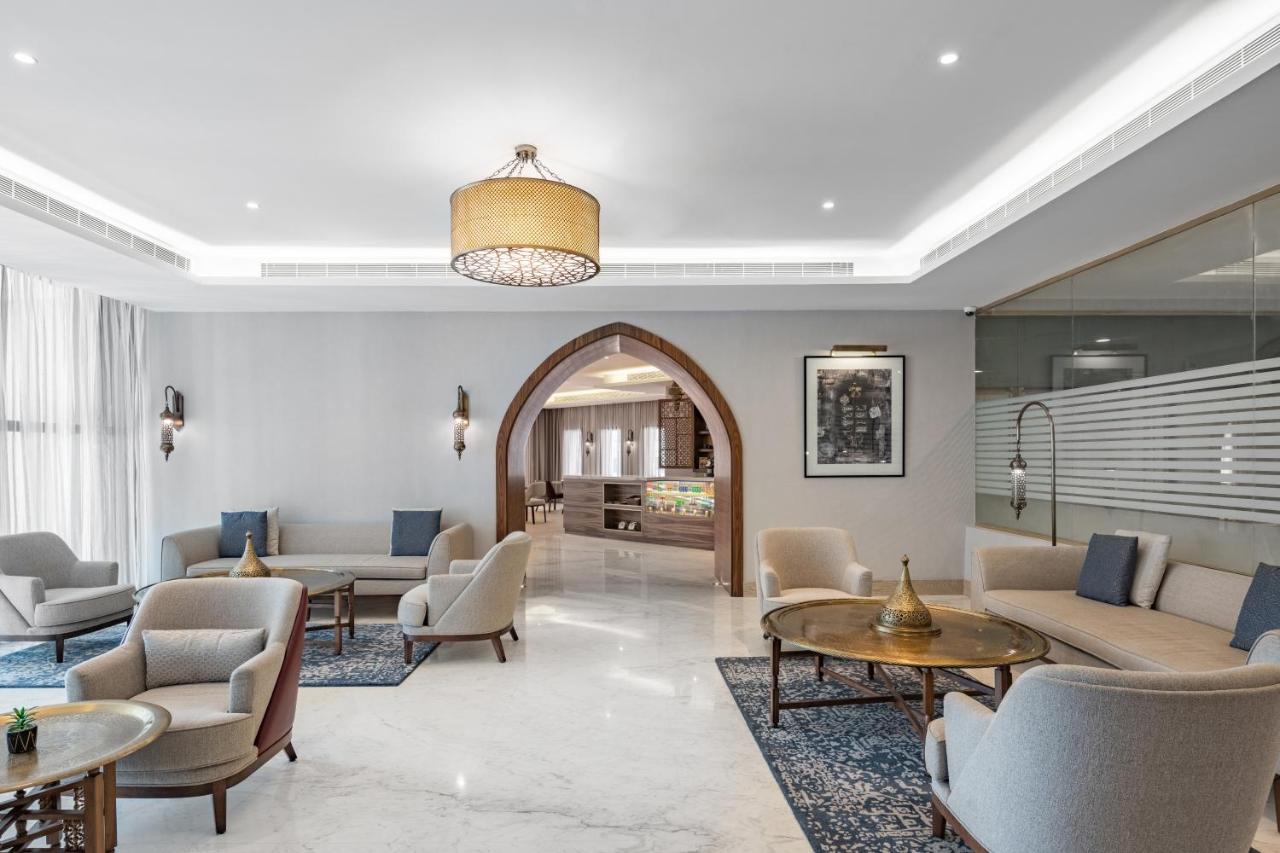 Makarem Ajyad Makkah Hotel Мека Екстериор снимка The photo shows a modern and elegantly designed lounge area. It features light-colored walls and marble flooring, complemented by stylish furniture including several armchairs and small tables. The lighting is soft, provided by a decorative chandelie