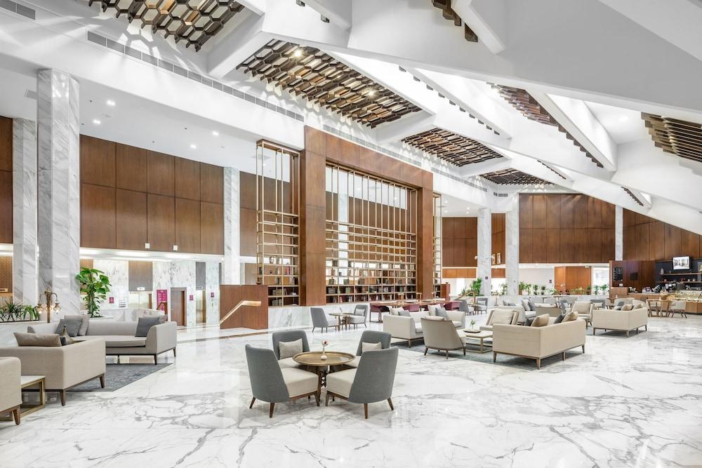 Makarem Ajyad Makkah Hotel Мека Екстериор снимка The photo shows a spacious and modern hotel lobby. It features a high ceiling with an elegant design, incorporating wooden accents and contemporary lighting. The floor is made of white marble, creating a bright and open atmosphere. 

In the foregroun