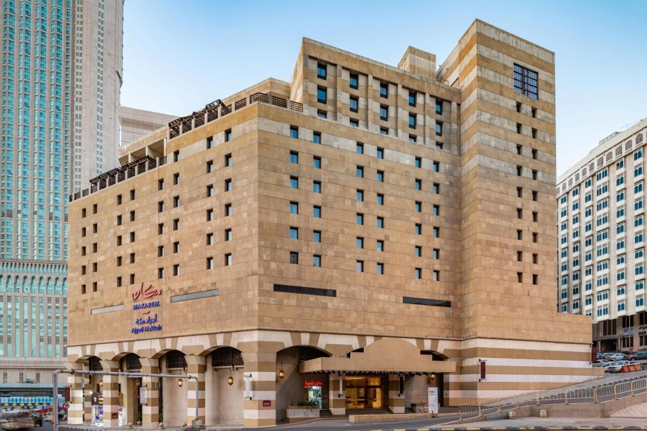 Makarem Ajyad Makkah Hotel Мека Екстериор снимка The photo shows a multi-story building with a distinctive architectural style. The facade features a combination of textured stone and concrete, giving it a contemporary yet somewhat traditional appearance. The building has multiple windows arranged 