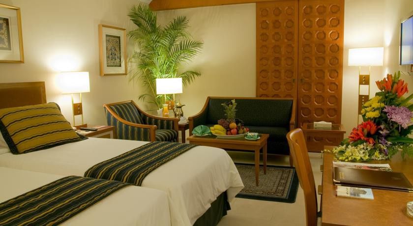 Makarem Ajyad Makkah Hotel Мека Екстериор снимка The photo shows a cozy hotel room that features two single beds with white linens and dark green and striped blankets. There is a decorative rug on the floor. Against one wall, there is a large wooden partition with a distinctive geometric pattern. T