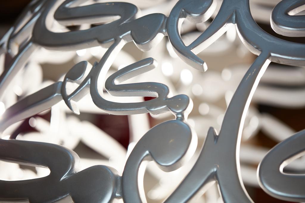 Makarem Ajyad Makkah Hotel Мека Екстериор снимка The photo shows a close-up of a white, artistic structure or piece of decor that features intricate, stylized lettering. The letters are intertwined and have a fluid, modern design. The focus on the details reveals the elegance of the curves and shap